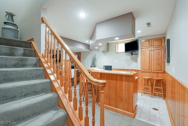 indoor wet bar with wainscoting, wooden walls, recessed lighting, and stairway