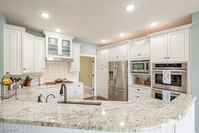 kitchen with stainless steel appliances, white cabinetry, tasteful backsplash, a peninsula, and recessed lighting