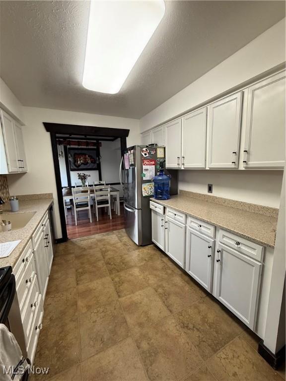 5460 Coronada Dr, Mentor-On-The-Lake, OH 44060 - kitchen with freestanding refrigerator, a sink, white cabinets, light countertops, and stove