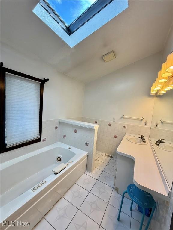 5460 Coronada Dr, Mentor-On-The-Lake, OH 44060 - bathroom featuring marble look tiles, a skylight, a garden tub, tile walls, and vanity