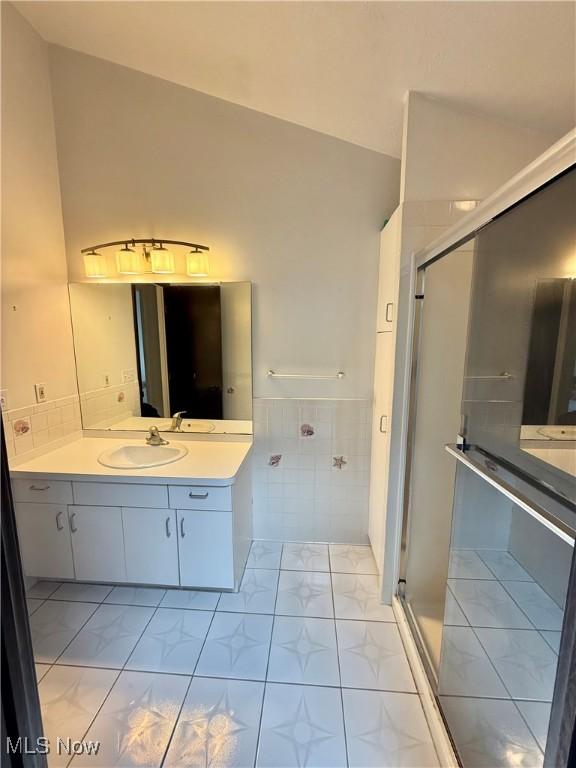 5460 Coronada Dr, Mentor-On-The-Lake, OH 44060 - bathroom with a stall shower, tile walls, vanity, tile patterned floors, and a wainscoted wall