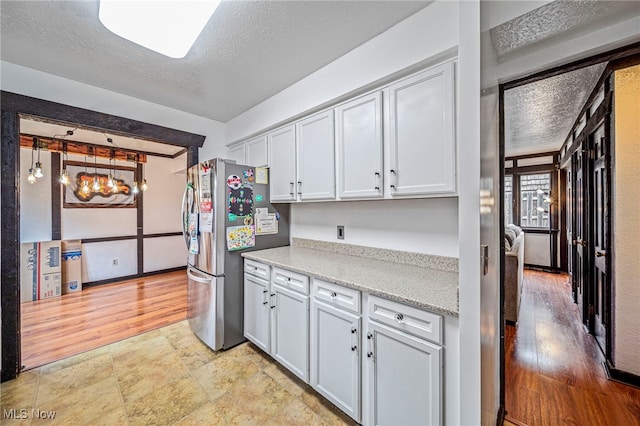 5460 Coronada Dr, Mentor-On-The-Lake, OH 44060 - kitchen with freestanding refrigerator, a textured ceiling, light stone countertops, and white cabinetry