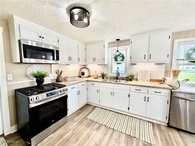 4812 Irma Ave, Youngstown, OH 44514 - kitchen featuring stainless steel appliances, a sink, light wood finished floors, white cabinetry, and a textured ceiling