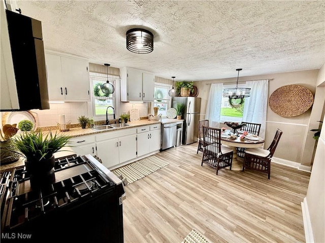 4812 Irma Ave, Youngstown, OH 44514 - kitchen with a sink, appliances with stainless steel finishes, light wood-style floors, a textured ceiling, and a chandelier
