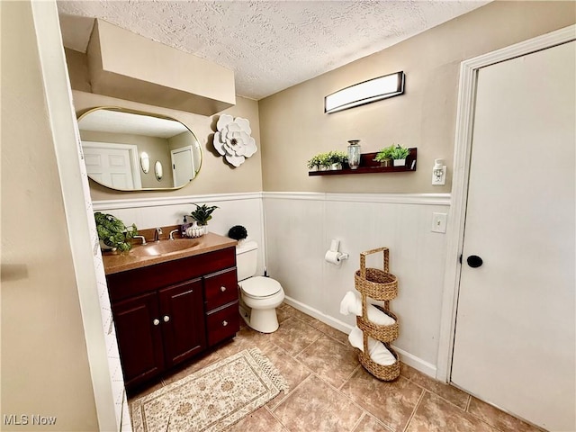 4812 Irma Ave, Youngstown, OH 44514 - bathroom with toilet, vanity, a textured ceiling, wainscoting, and tile patterned floors