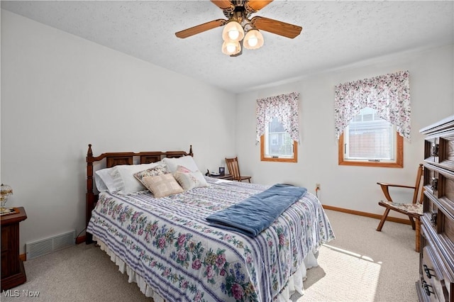 carpeted bedroom with a textured ceiling, baseboards, and a ceiling fan