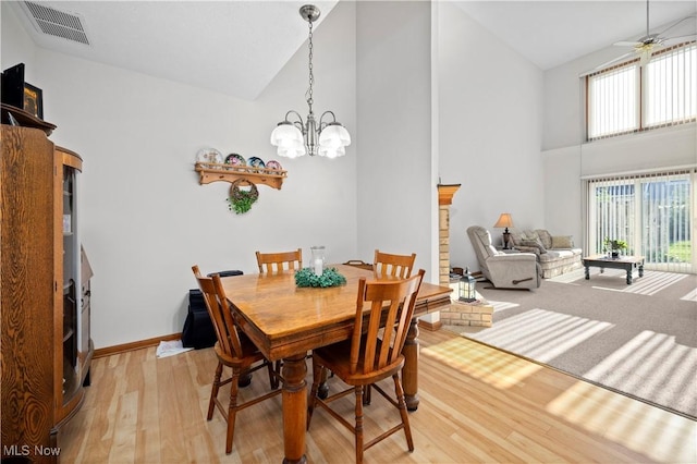 dining area featuring high vaulted ceiling, healthy amount of natural light, light wood-style floors, a chandelier, and ceiling fan