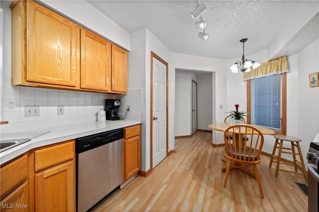 kitchen with stainless steel dishwasher, backsplash, a chandelier, light wood-style floors, and light countertops