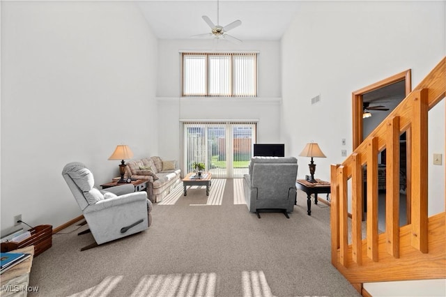 living room with ceiling fan, a high ceiling, and carpet