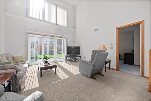 living room featuring plenty of natural light, carpet floors, a high ceiling, and baseboards