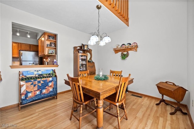 dining room featuring light wood-style flooring, a chandelier, and baseboards