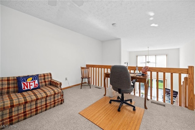 carpeted office featuring a textured ceiling, baseboards, and a ceiling fan