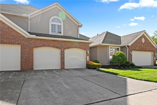 traditional home with brick siding, a garage, roof with shingles, and concrete driveway