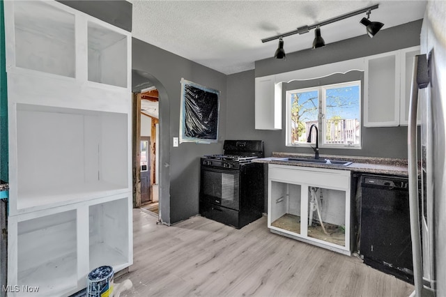 563 Mill St, Conneaut, OH 44030 - kitchen with black appliances, a sink, arched walkways, light wood-type flooring, and white cabinetry