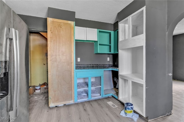 563 Mill St, Conneaut, OH 44030 - kitchen featuring light wood-style flooring, arched walkways, dark countertops, and a textured ceiling