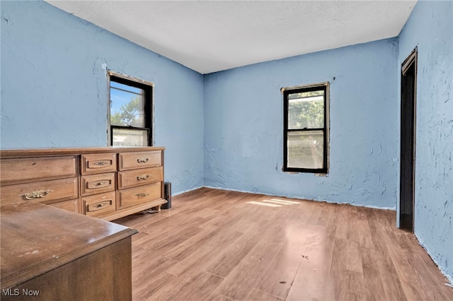 563 Mill St, Conneaut, OH 44030 - bedroom with light wood-style floors, a textured wall, and a textured ceiling