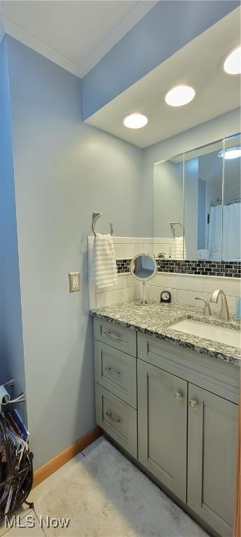 bathroom with vanity, ornamental molding, curtained shower, decorative backsplash, and baseboards