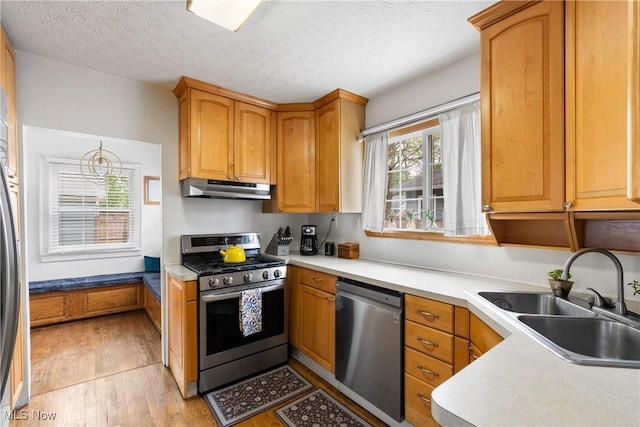 211 Harcourt Dr, Akron, OH 44313 - kitchen featuring appliances with stainless steel finishes, under cabinet range hood, a sink, light wood finished floors, and a textured ceiling