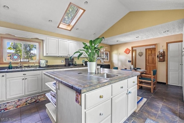 2854 Wells Lock Rd, Elizabeth, WV 26143 - kitchen with a sink, a skylight, white cabinets, a kitchen island with sink, and high vaulted ceiling