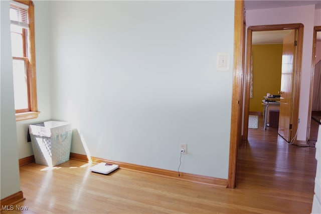 spare room featuring wood finished floors, baseboards, and healthy amount of natural light