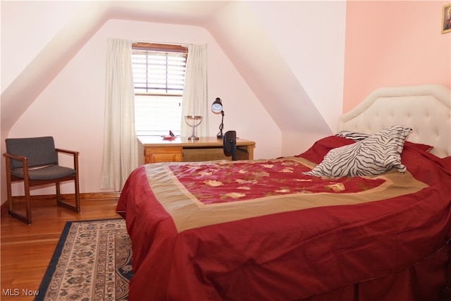 bedroom featuring wood finished floors and lofted ceiling