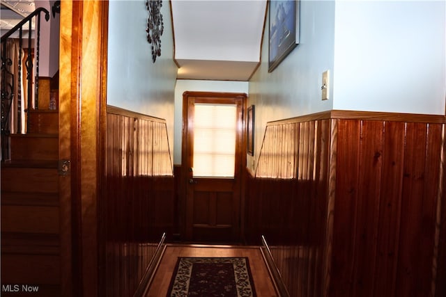entryway featuring wainscoting, wooden walls, and wood finished floors