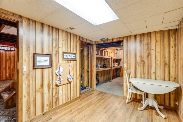 office space with wooden walls, wood finished floors, and a paneled ceiling