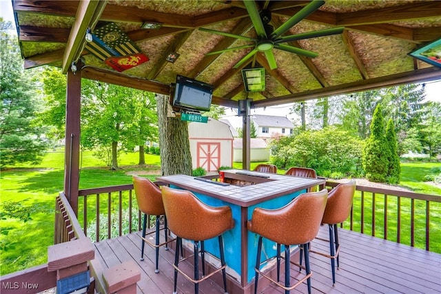 deck featuring a yard, a storage unit, an outbuilding, and outdoor dining space