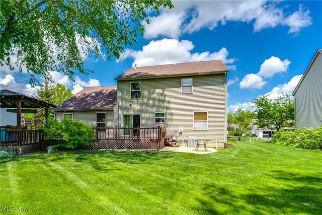 back of house featuring a wooden deck, a lawn, and a patio