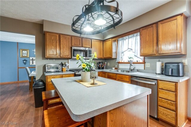 kitchen with stainless steel appliances, a sink, light countertops, and a textured ceiling