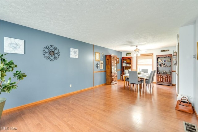 dining area featuring a ceiling fan, a textured ceiling, wood finished floors, and baseboards