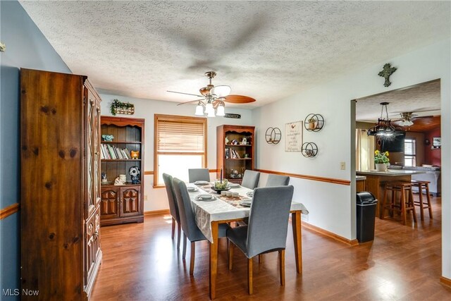 dining area featuring ceiling fan, plenty of natural light, a textured ceiling, and wood finished floors