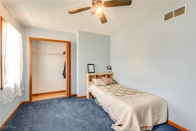 bedroom featuring carpet, a closet, a ceiling fan, baseboards, and a textured ceiling