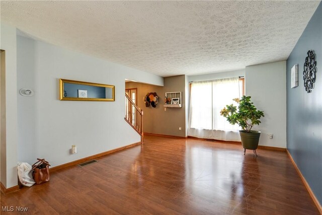spare room with wood finished floors, baseboards, stairs, and a textured ceiling