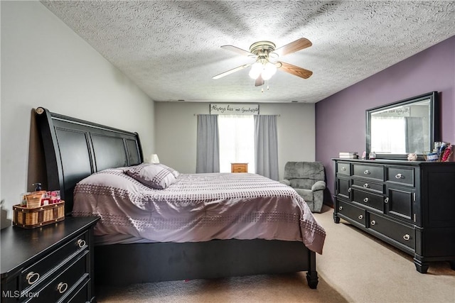bedroom featuring light colored carpet, a textured ceiling, and a ceiling fan