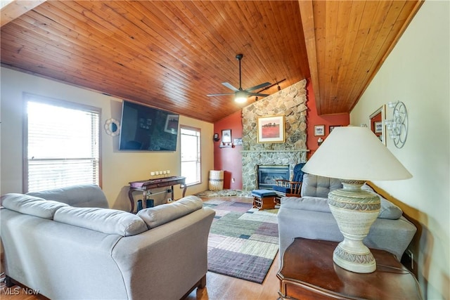 living room featuring wooden ceiling, vaulted ceiling, a stone fireplace, wood finished floors, and a ceiling fan