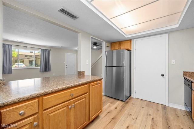 kitchen featuring freestanding refrigerator, light wood-style floors, dishwasher, brown cabinetry, and light stone countertops