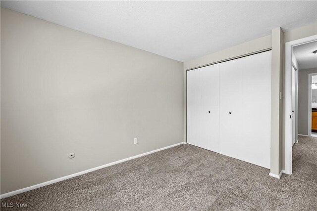 unfurnished bedroom featuring carpet, a closet, and baseboards