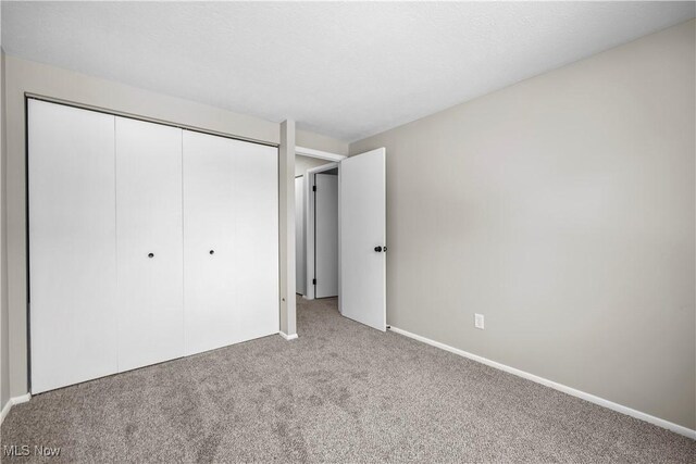 unfurnished bedroom with carpet, a closet, and baseboards