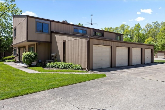 townhome / multi-family property featuring community garages, a front lawn, and cooling unit