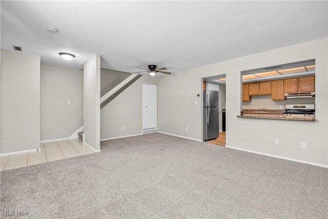 unfurnished living room with light colored carpet, ceiling fan, stairs, and baseboards