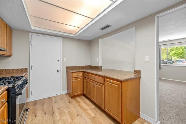 kitchen featuring range with gas cooktop, light wood-style flooring, baseboards, and brown cabinets