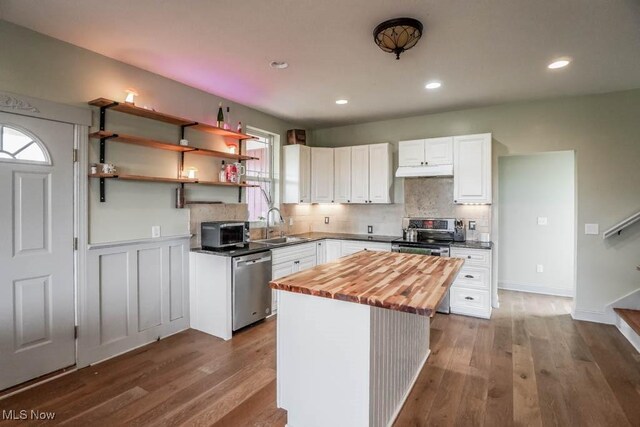 7841 State St NE, Louisville, OH 44641 - kitchen featuring appliances with stainless steel finishes, wood counters, a sink, under cabinet range hood, and white cabinets