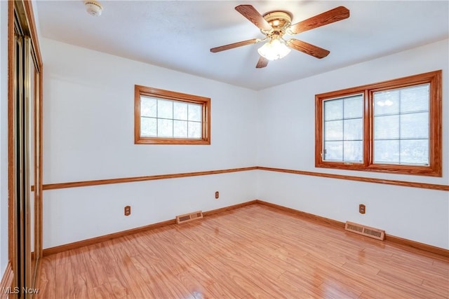 spare room with healthy amount of natural light, light wood-style floors, and baseboards