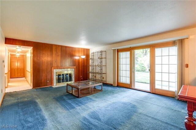 living room with wooden walls, carpet floors, a fireplace, and baseboards