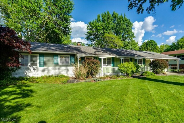 single story home with a front yard, a chimney, and covered porch