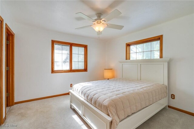 bedroom featuring light colored carpet, baseboards, and ceiling fan