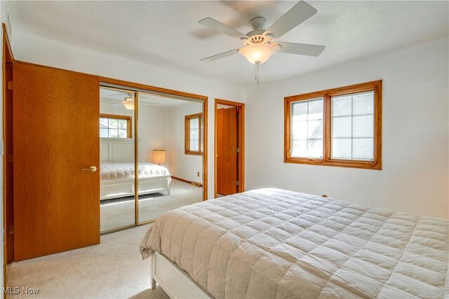 bedroom with light colored carpet, a closet, and a ceiling fan