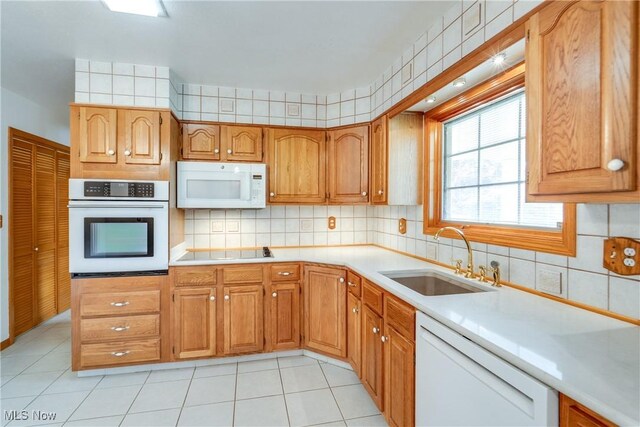 kitchen with white appliances, a sink, light countertops, and light tile patterned floors