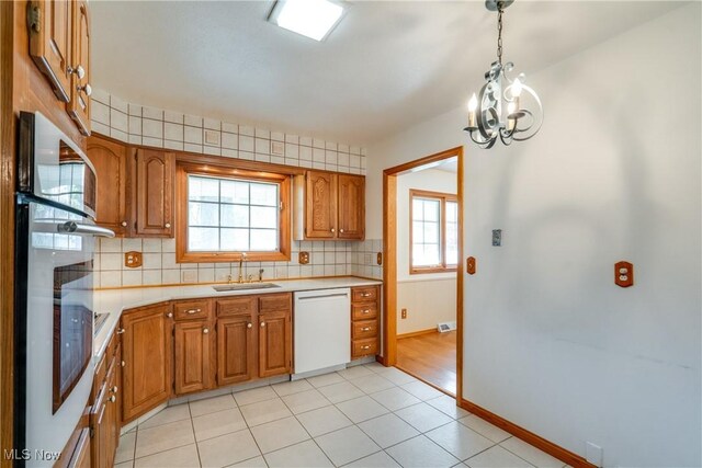 kitchen featuring dishwasher, wall oven, a sink, and brown cabinetry